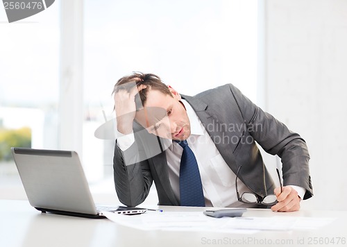 Image of businessman with computer, papers and calculator