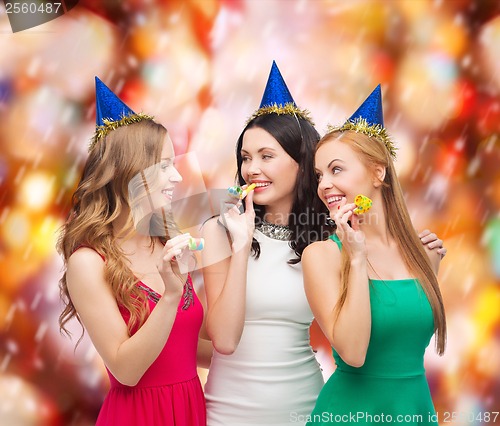 Image of three smiling women in hats blowing favor horns