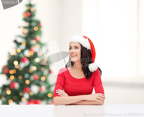 Image of surprised woman in santa helper hat looking up