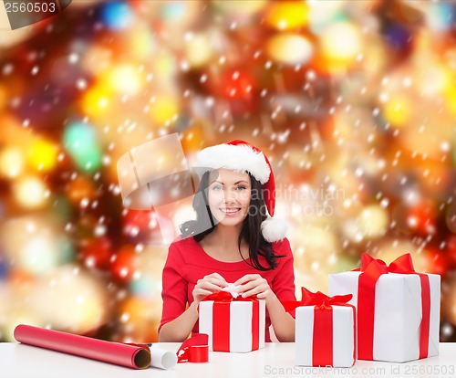 Image of woman in santa helper hat with many gift boxes