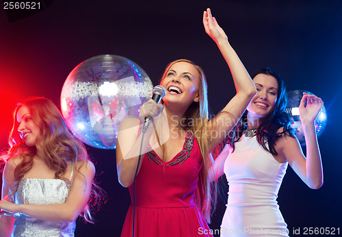 Image of three smiling women dancing and singing karaoke