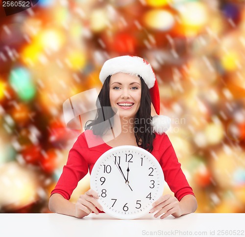 Image of woman in santa helper hat with clock showing 12