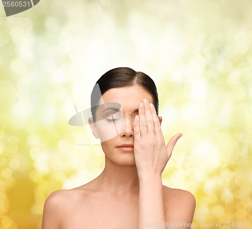Image of calm young woman covering face with hand