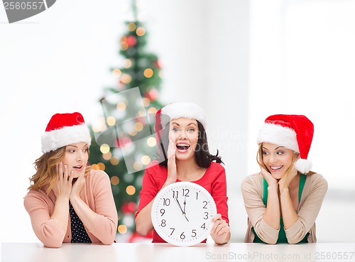 Image of women in santa helper hats with clock showing 12