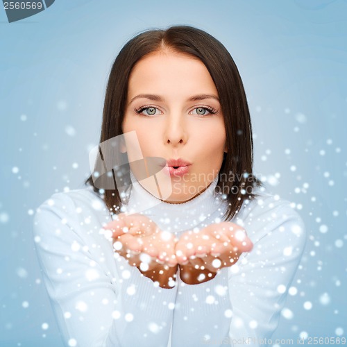 Image of happy woman in white sweater blowing on palms