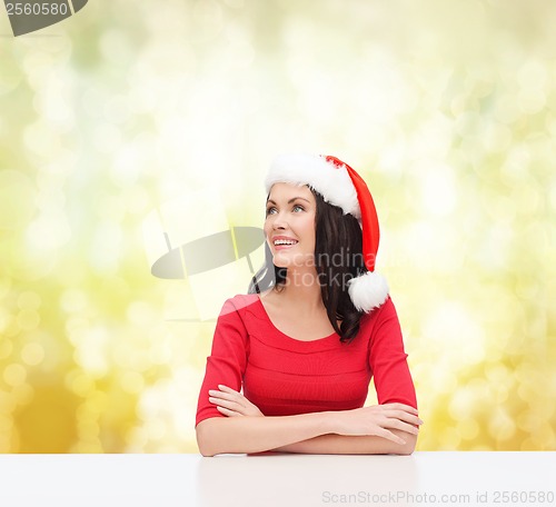 Image of surprised woman in santa helper hat looking up