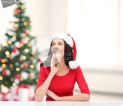 Image of surprised woman in santa helper hat looking up