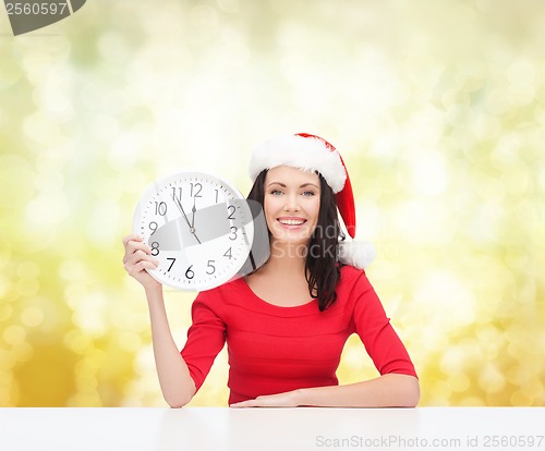 Image of woman in santa helper hat with clock showing 12