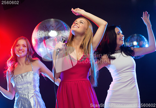 Image of three smiling women dancing and singing karaoke