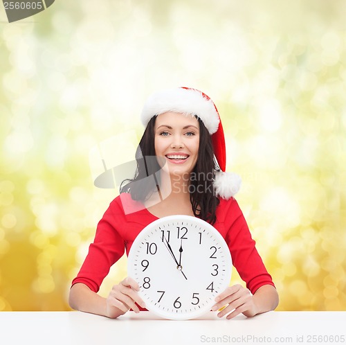 Image of woman in santa helper hat with clock showing 12