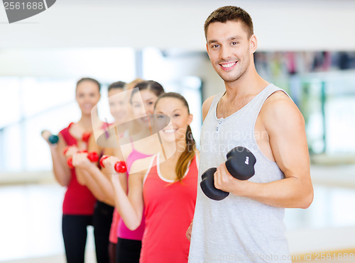 Image of group of smiling people with dumbbells in the gym