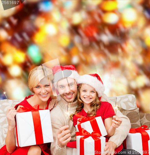 Image of smiling family holding gift boxes and sparkles