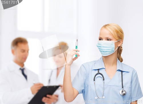 Image of female doctor or nurse in mask holding syringe