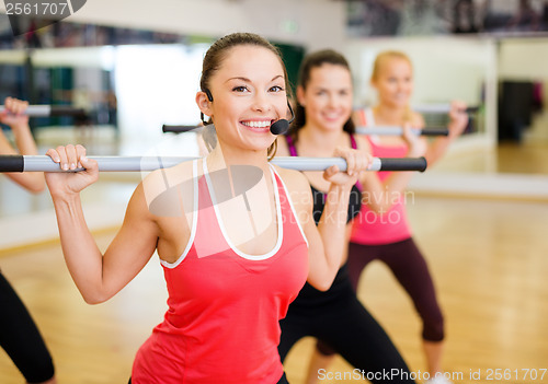 Image of group of smiling people working out with barbells