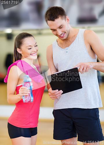 Image of smiling male trainer with woman in the gym