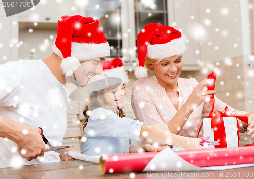 Image of smiling family in santa helper hats with gift box