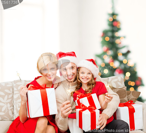 Image of smiling family holding gift boxes and sparkles