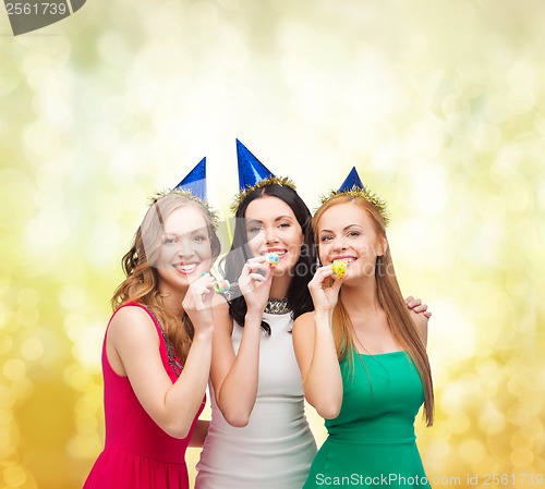 Image of three smiling women in hats blowing favor horns