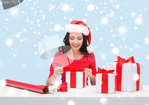 Image of woman in santa helper hat with many gift boxes