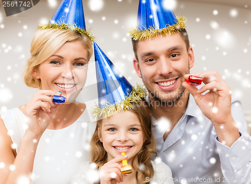 Image of smiling family in blue hats blowing favor horns