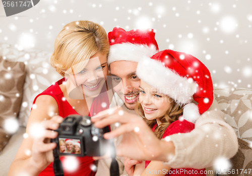 Image of smiling family in santa helper hats taking picture