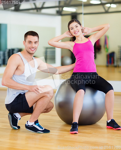 Image of male trainer with woman doing crunches on the ball