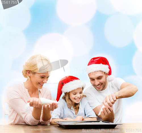 Image of happy family in santa helper hats making cookies