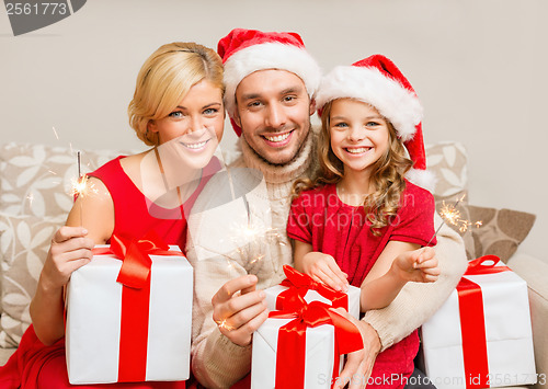 Image of smiling family holding gift boxes and sparkles