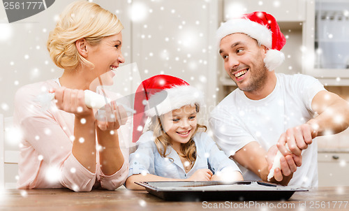 Image of happy family in santa helper hats making cookies