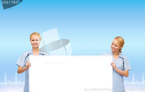 Image of smiling female doctors or nurses with blank board