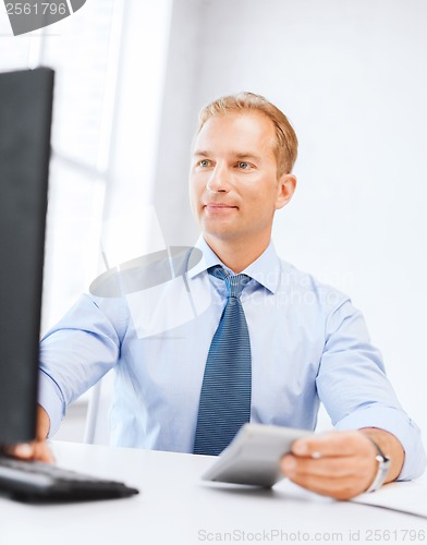 Image of businessman with calculator, computer and papers