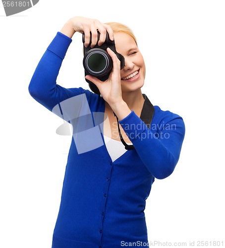 Image of smiling woman taking picture with digital camera