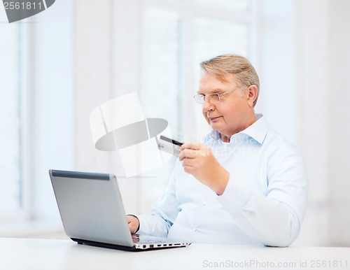 Image of old man with laptop and credit card at home