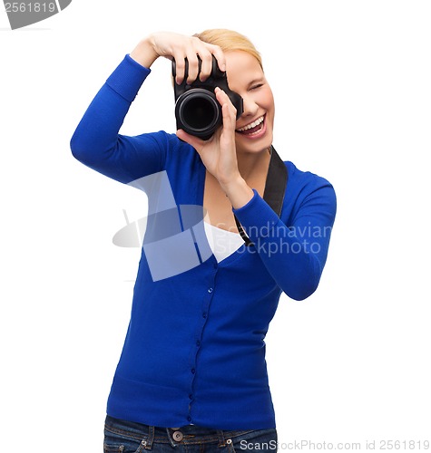 Image of smiling woman taking picture with digital camera