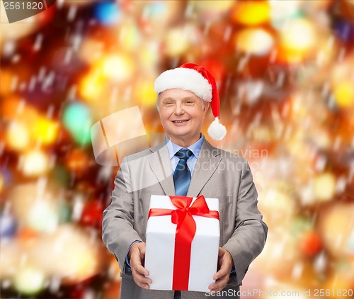 Image of smiling man in suit and santa helper hat with gift