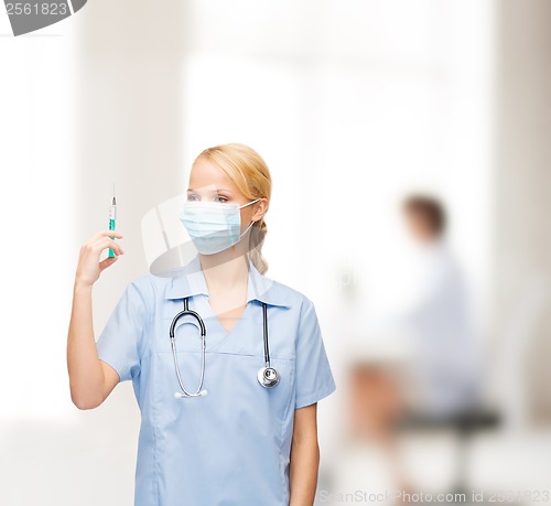 Image of female doctor or nurse in mask holding syringe