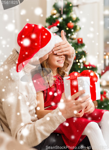 Image of smiling father surprises daughter with gift box