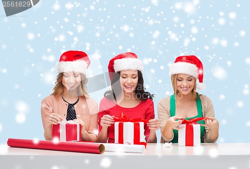 Image of smiling women in santa helper hats with gift boxes