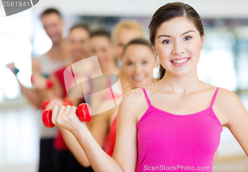 Image of group of smiling people with dumbbells in the gym