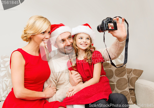 Image of smiling family in santa helper hats taking picture