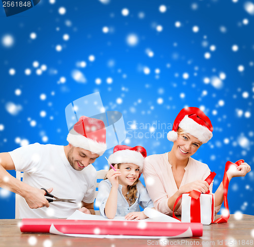 Image of smiling family in santa helper hats with gift box