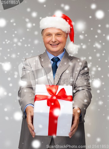 Image of smiling man in suit and santa helper hat with gift