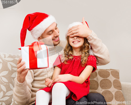Image of smiling father surprises daughter with gift box