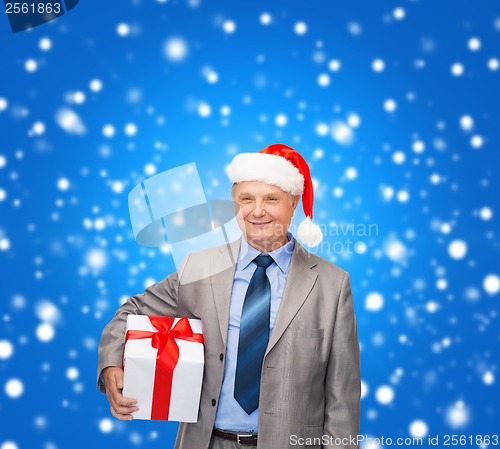 Image of smiling man in suit and santa helper hat with gift