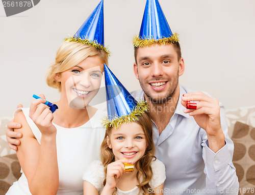 Image of smiling family in blue hats blowing favor horns