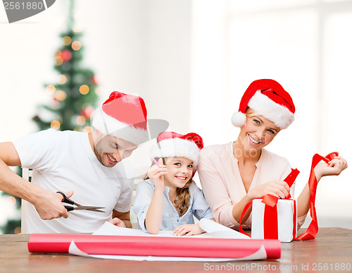 Image of smiling family in santa helper hats with gift box