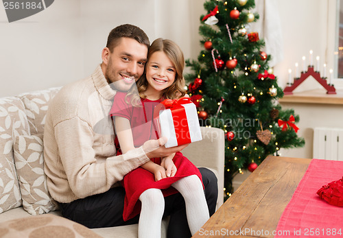 Image of smiling father and daughter holding gift box