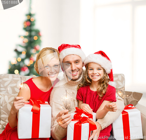 Image of smiling family holding gift boxes and sparkles