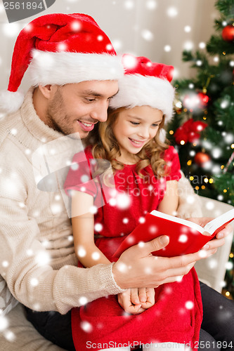 Image of smiling father and daughter reading book