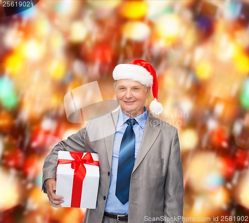 Image of smiling man in suit and santa helper hat with gift